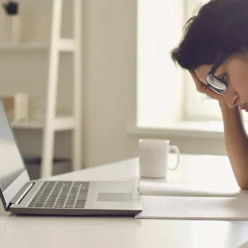 Photo of woman looking frustrated at paper and laptop for 5 mistakes you're making with affiliate marketing.