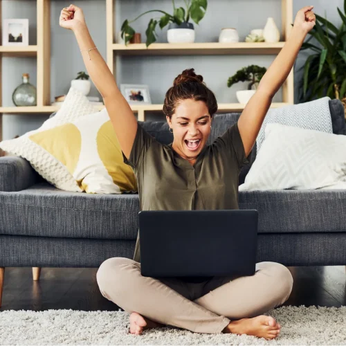 Woman celebrating with laptop because she joined Shared Vision.